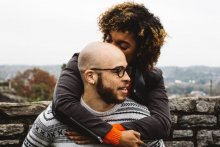 Photo credit: Justin Follis. A woman hugs a man from behind 