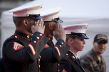 A photo of two men and a woman in U.S. Marine Corps dress uniform, saluting. 