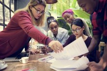 A photo of several young people working on documents across a table