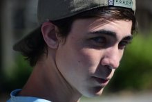 Photo credit: Taylor Smith. A white youth in a baseball cap looks at the camera