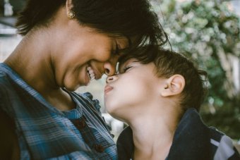 Photo credit: Bruno Nascimento. A woman smiles and embraces a young child