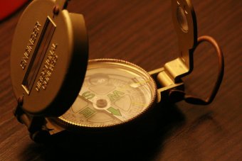 A modern engineer compass open on top of a wooden table.