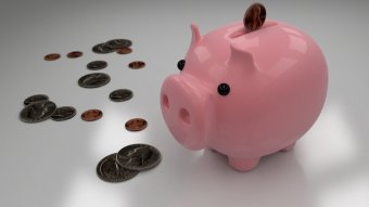 A pink piggy bank on a white table surrounded by U.S. coins.