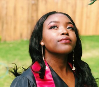 Photo credit: Princess Olanrewaju. A black woman in a graduation gown looks up.