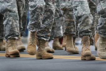 A photo of people, from the knees down, wearing camoflague uniforms and tan combat boots.