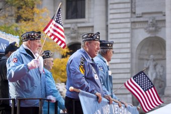 Several older men in Korean War veterans caps march in a parade